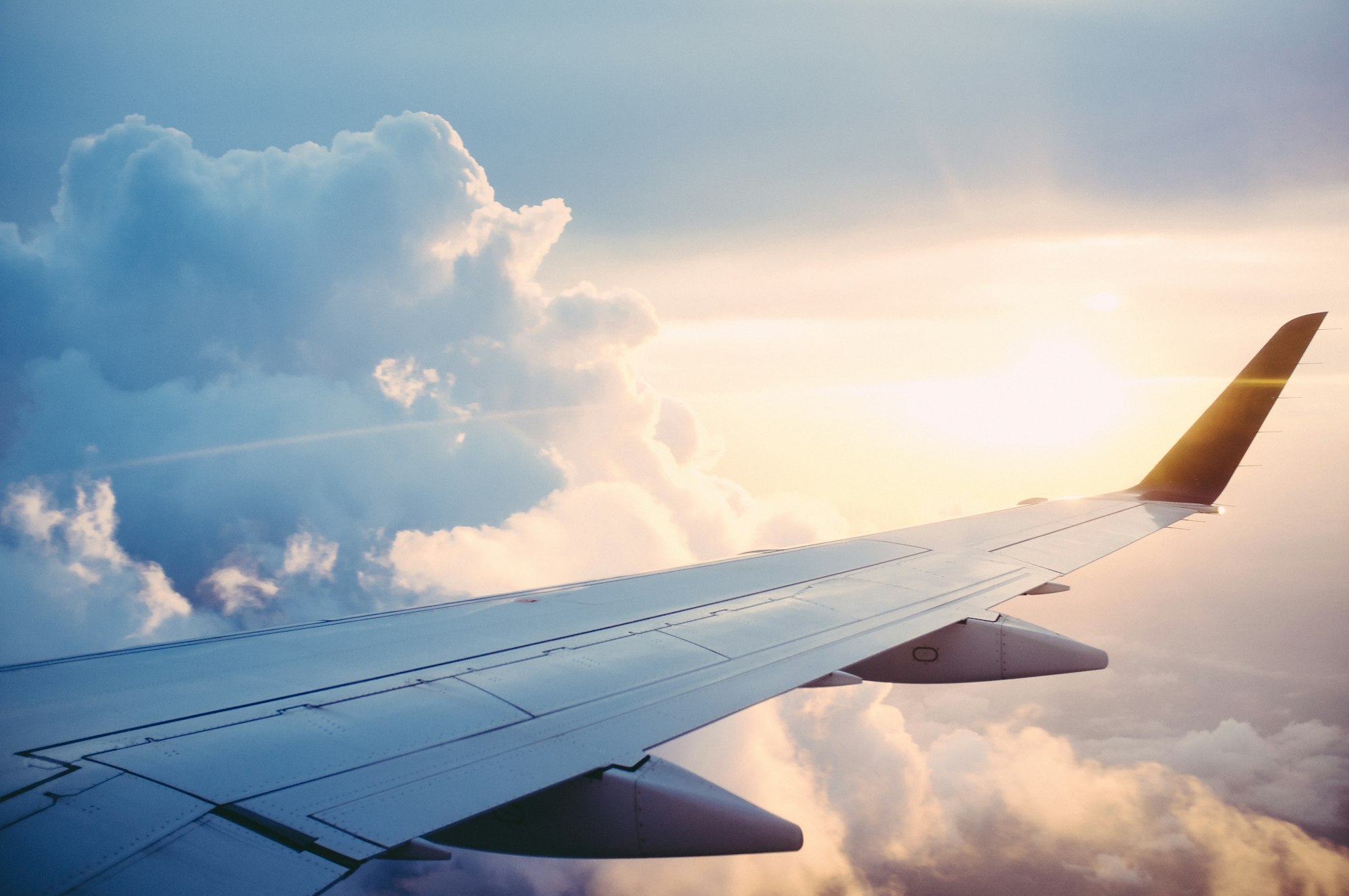 Aircraft wing in late light above a layer of cloud